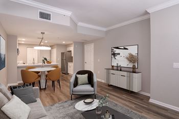 A modern living room with a grey sofa, a grey armchair, a white coffee table, and a grey rug at Floresta, Jupiter, FL